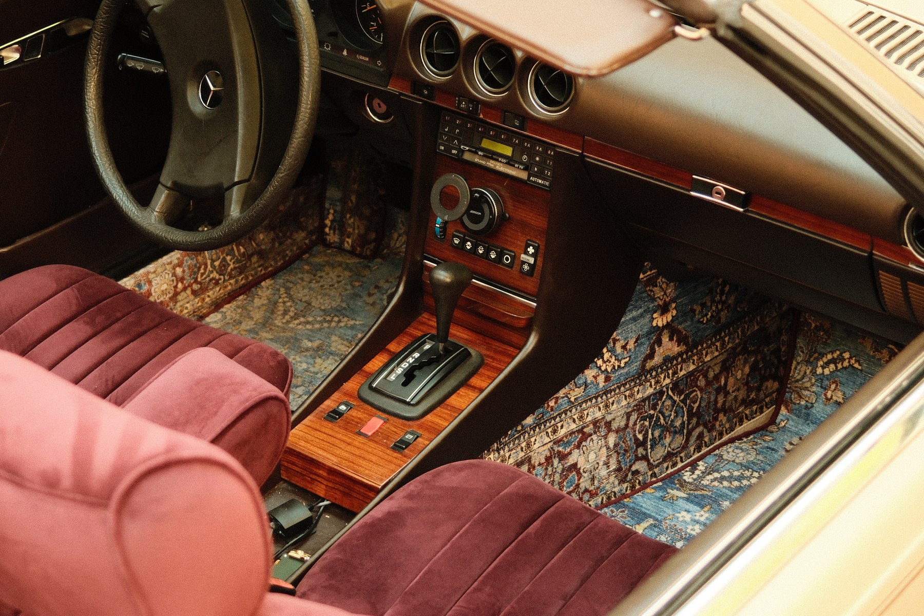 Mercedes 380 SL interior — burgundy velvet seats, Persian carpet floor and walnut dashboard, available for hire in Lisbon
